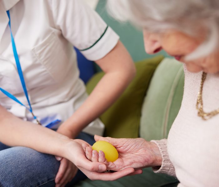 Female,Physiotherapist,Getting,Senior,Woman,To,Squeeze,Rubber,Ball,At Female,Physiotherapist,Getting,Senior,Woman,To,Squeeze,Rubber,Ball,At
