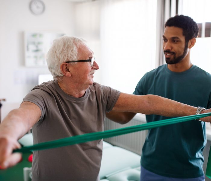 Young,Physiotherapist,Exercising,With,Senior,Patient,In,A,Physic,Room Young,Physiotherapist,Exercising,With,Senior,Patient,In,A,Physic,Room